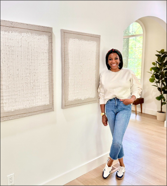 photo of Zoey Belton standing against wall wearing blue jeans and a white sweater